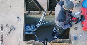 Worker made a break-in with an electric demolition hammer in the reinforced concrete shaft of the fiber optic cable line. Open triangular cast iron manhole covers