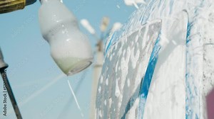 Cleaning the tractor with a high pressure washer. Foam comes out of the washer. Slow motion. Close-up of a detergent container. 4K