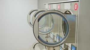 Close up view of tunnel washers with open circular doors in modern laundry facility as lights go off, highlighting stainless steel design, and reflective surfaces in clean environment | Premium Stock Video Footage