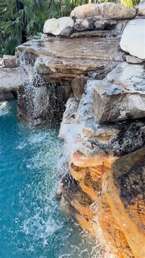 This tropical lagoon in Florida was designed to mimic an old Florida swimming hole. Featuring a natural rock grotto waterfall, lush landscaping, and natural rock paths leading you from one destination to another. #insanepools #lucaslagoons #pool #lagoon | Lucas Lagoons