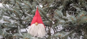 Scandinavian gnome on the christmas tree branches in the snow. First snow falling in the europe. Winter in scandinavian country. New year concept. Winter video card.