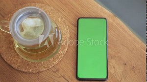 Smartphone place on table wood with green screen, Close-up the cell phone is on the brown table in the restaurant with chroma key, Green screen telephone, and top view