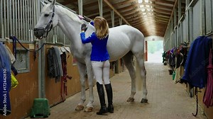 Middle-aged woman with her horse in a stall