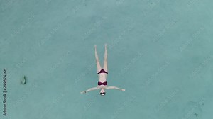 Beautiful young woman swimming, lying on a water surface in crystal clear ocean Stock Video