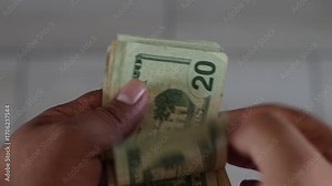 Cashier counting one hundred, twenty and five dollar bills