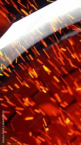 Numerous shining particles being emitted from a stove pipe. Orange and yellow sparks flying fast at black backdrop. Vertical video