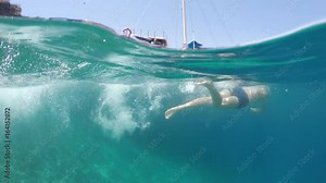 swimmer swims into the sea, half underwater close up, raw, 4k