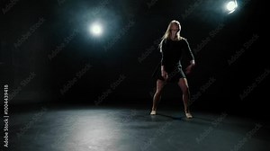 Modern ballerina dancing in darkness, graceful lady jumping, slow motion. Talented female dancer rehearsing contemporary choreography in dark dance class, silhouette of pretty slender lady in black
