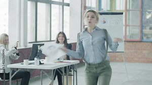 The girl manager is walking around the office, dancing and throwing documents. Creative business space in the loft style. Coworking. Office life. Hand camera