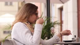 Woman sit smoking cigarette at the street cafe table while drinking...