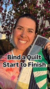 Quilt reveal at the end! Let me show you how to bind a quilt — it’s easier than it looks! First, gather your supplies: binding strips, scissors or a rotary cutter, some clips, and of course, your sewing machine. Start by sewing your binding strip to the front of the quilt, raw edges lined up. Go all the way around, and stop just before the corners. For the corners, fold the binding up and then down to create this nice mitered angle — trust me, it’s worth it. Once it’s all attached to the front, 