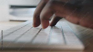 black man works at a computer. Typing text on the keyboard
