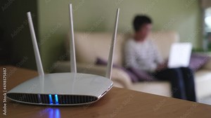 Selective focus at router. Internet router on working table with blurred man using tablet at the background. Fast and high speed internet connection from fiber line with LAN cable connection. Stock Video