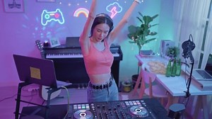 Asian young woman DJ mixing and scratching on music mixer controller. Attractive female musician DJ having fun mixing music on console touching buttons and playing electronic music at neon party.