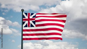 Grand union flag flutters in the wind. Historycal 1775 USA flag on cloudy background.