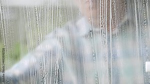Man Washing and Cleaning a Double-Glazed Window at Home using a Sponge and Disinfectant Foam. Household Chores.