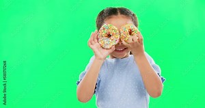 Donut on eyes, smile and child on green background with cake over face for funny, meme and comic. Food, excited kid and isolated happy girl with sweets, dessert treats and sugar doughnuts in studio