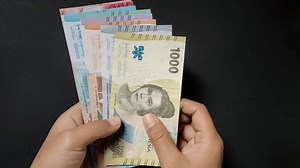 The man shows the latest issue of Indonesian banknotes, ranging from 1,000 to 100,000 nominal. Rupiah currency conceptual isolated on a black background.