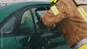 Car accident rescue, firefighter breaking the glass on the car and checking for the injured people. Close up, Slow motion shot.