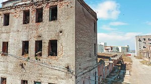 Ruined building without windows and roof outside. Exterior of a broken-down building in the desolate part of the city.