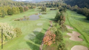 Aerial view of golf course with a rich green turf, putting green, sand bunker and water hazards.