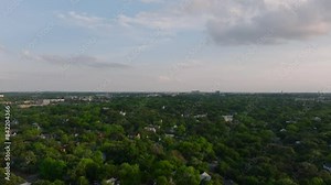 Bird's Eye view of a residential neighborhood showcases green landscapes and houses against a partly cloudy sky. Harmony of nature and architecture in an American city