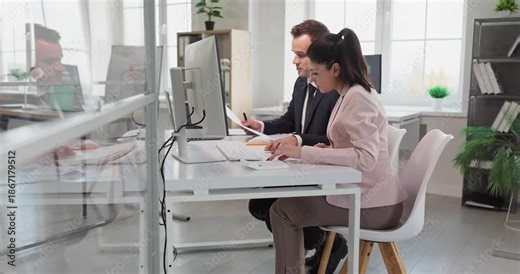 Manager and coworker in office meeting discussion. They review analytics at a computer and plan tasks. A mentor guides training and improves workflow. Business collaboration and mentorship concept.