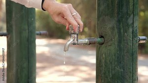 Stop senseless consumption of water on street in metal tap. hand close open faucet in nature from which water flow. environmental problems of saving water and energy in world require solutions.