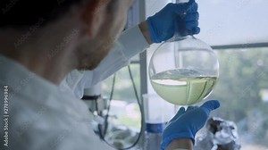 Scientist mixing and spinning liquid inside round-bottom flask in a laboratory