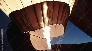 The launch of a large hot air balloon, close-up, with the flames filling it with hot air at dawn during twilight. Slow motion