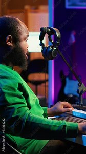 Vertical Video African american sound engineer using midi controller notes to add audio effects in post production, editing tracks with digital software and mixing console. Male musician in home