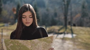 Young beautiful woman hiking on a mountain trail, stops and checks map for directions. Woman with old map in mountains