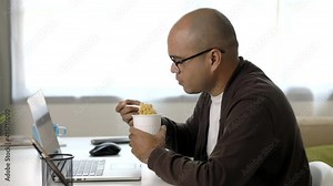 Young asian businessman working with laptop. Indian freelancer eating instant noodle while working. He work at home. He had to hurry and finish his work.