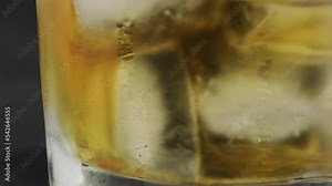 Shot of hand pouring cold tequila from a bottle with lemon and salt on black background. A glass of tequila with lemon slices and splashing. Alcoholic drink concept. selective focus.