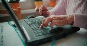 Senior citizen working in front of laptop and typing on the keyboard