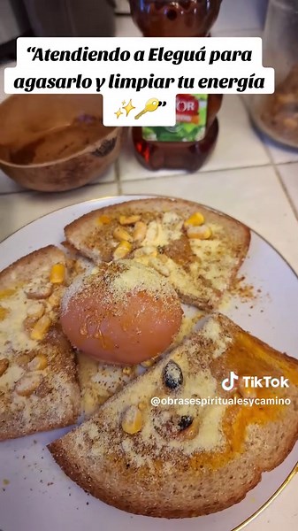 Hoy les muestro cómo preparo una atención especial a Eleguá, no para pedirle, sino para honrarlo y mantener nuestros caminos abiertos ✨🙏🏾. En un plato colocamos: • 3 pedacitos de pan • Maíz, jutía y pescado ahumado • Harina de maíz • Miel • Un huevo en el centro con las mismas preparaciones • Una jícara con otí y otra con vino seco Esto se mantiene 3 días como ofrenda y atención, tal como siempre les explico. Pasados los 3 días, todo el contenido y el huevo se envuelve en un papel traza, y con