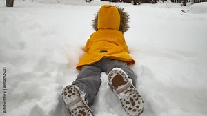 happy child playing on the snowy yard of a house in winter falling into the snow Stock Video