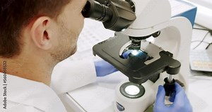 Using a microscope to examine the patients blood health condition. Microscope for blood examination at the clinic. Examining blood under the high-tech microscope equipment. Medical device.