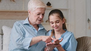 Old gray-haired grandmother reading fortune lines on laughing granddaughter hand. Young girl looks listens with interest. Process of fortune telling along the line on the palms chiromancy concept