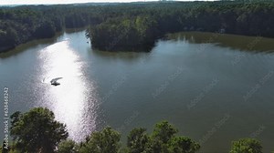 panning aerial footage of a gorgeous summer landscape at Proctor Landing park with rippling lake water, boats, green trees and grass with blue sky and clouds at Lake Acworth in Acworth Georgia USA