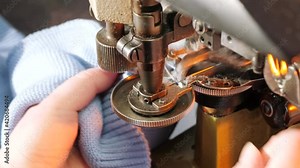 Female hands working on Tailoring. Clothes Making. Automated industrial Textile Sewing machine. Production of knitted garments. Fabric factory.