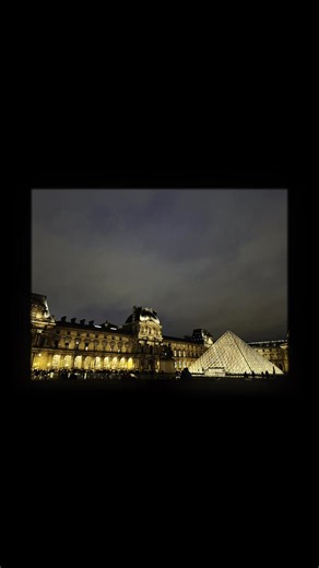 At night, the Louvre transforms into something almost unreal - a meeting point between silence, light, and centuries of history. The glass pyramid glows like a beacon in the darkness, reflecting the warm tones of the surrounding palace walls. Every step across the courtyard feels slower, more intentional, as if the city itself is inviting you to pause and breathe. The sky hangs heavy above Paris, but the golden illumination cuts through the night, turning the museum into a living sculpture. Peop