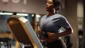 Beautiful black woman running on treadmill while working out in gym