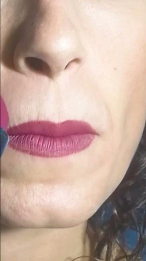 A seductive woman applying burgundy lipstick