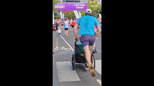 Father carries two young children across finish line in emotional moment