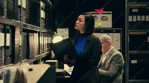 Private investigator searching for old case folders in archive room, comparing witness statements and interviews across multiple investigations. Detective works with classified notes. Camera B.