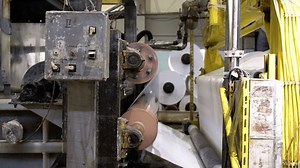 Drying wet paper sheet with hot mill machine in workshop closeup. Tissue pulp strip pressing with drying equipment at papermaking factory