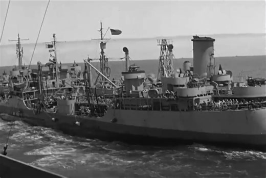 Archival footage of an underway replenishment at sea — a Brooklyn-class cruiser takes on fuel and supplies from a fleet oiler, gray hulls riding in parallel through rolling blue water. Lines are shot across, hoses rigged, and sailors work in rhythm amid the spray and wind. In those days, during refueling, the ship’s bands played music across the decks — a tradition that turned steel and salt into ceremony. Today the bands are gone, but the practice endures; now the songs come from loudspeakers, 