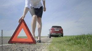 Woman installs emergency stop sign on highway. Close-up, blurred background.