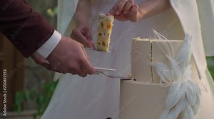 A person cutting a celebration cake. Bride and groom at wedding reception venue. Man and woman holding knife and cut a slice of dessert.
